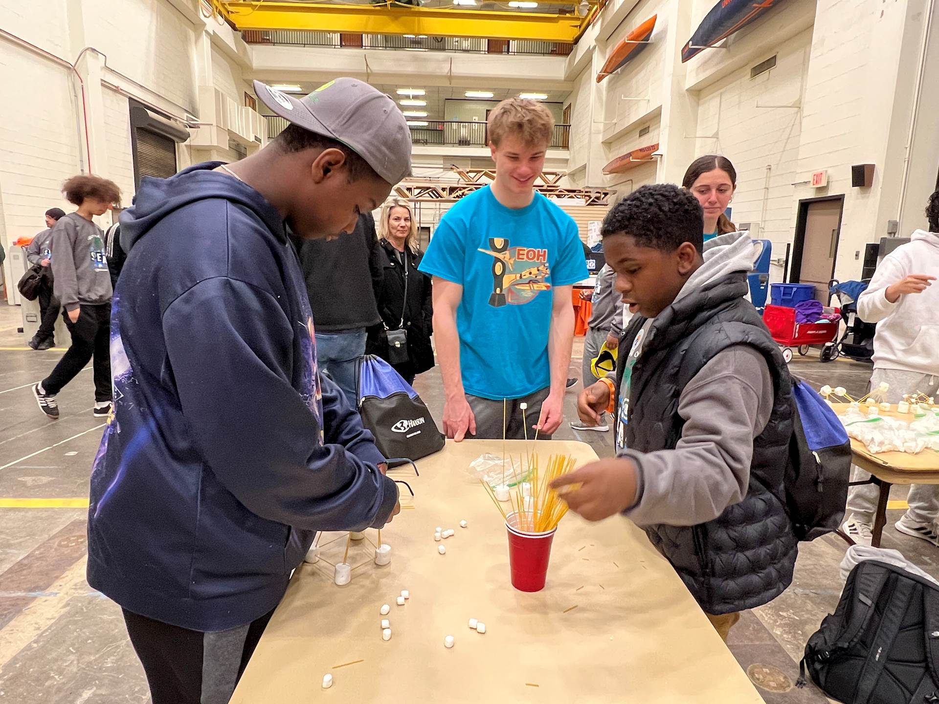 Two young students participating in a science-related activity with marshmallows and uncooked spaghetti noodles.