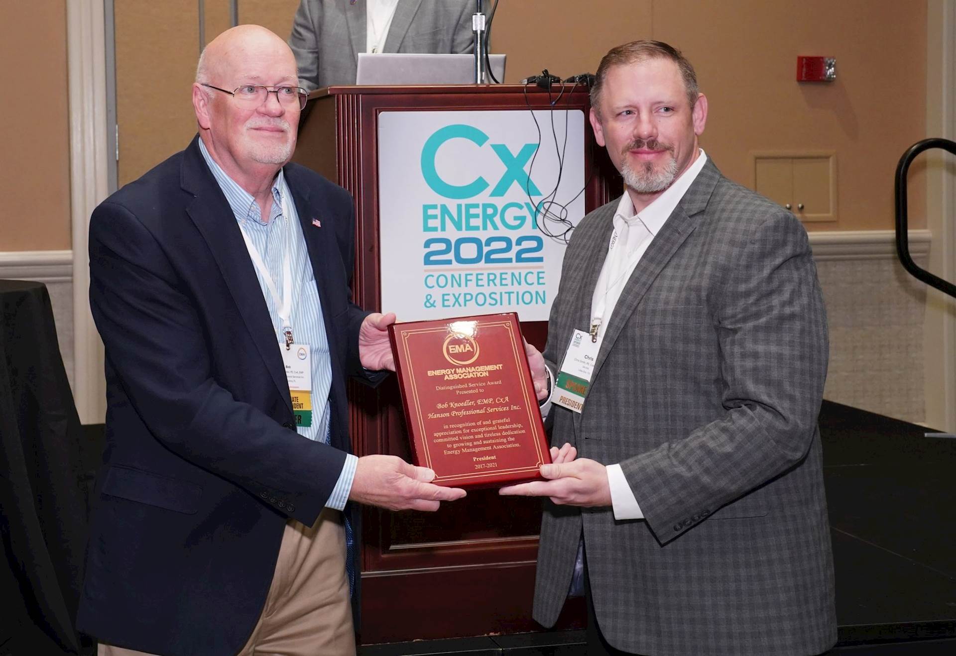 : Bob Knoedler accepting a plaque in front of a lectern with a CxEnergy sign