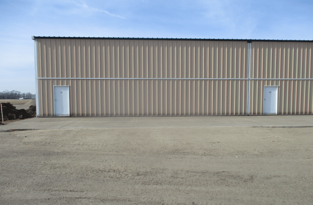 Exterior photo of an airport hangar with beige siding