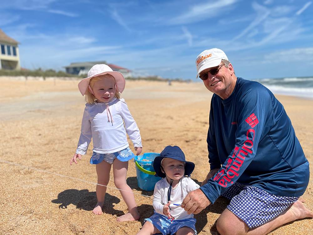 a photo of bill playing with his grandkids on the beach