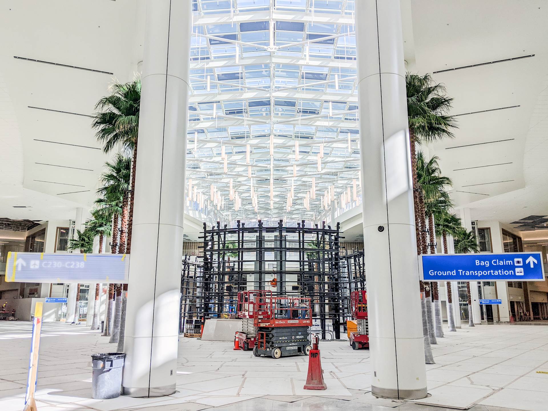 Columns and tall artificial palm trees flank a ceiling of skylights in the Orlando airport’s Terminal C