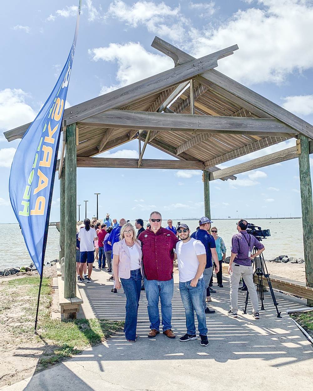 a photo of three hanson employees attending the ribbon cutting of a wooden pier in corpus christi, texas