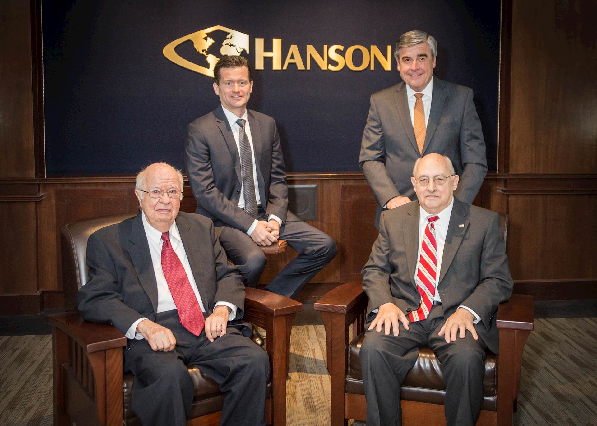 Four men in business suits posing for a photo in a board room