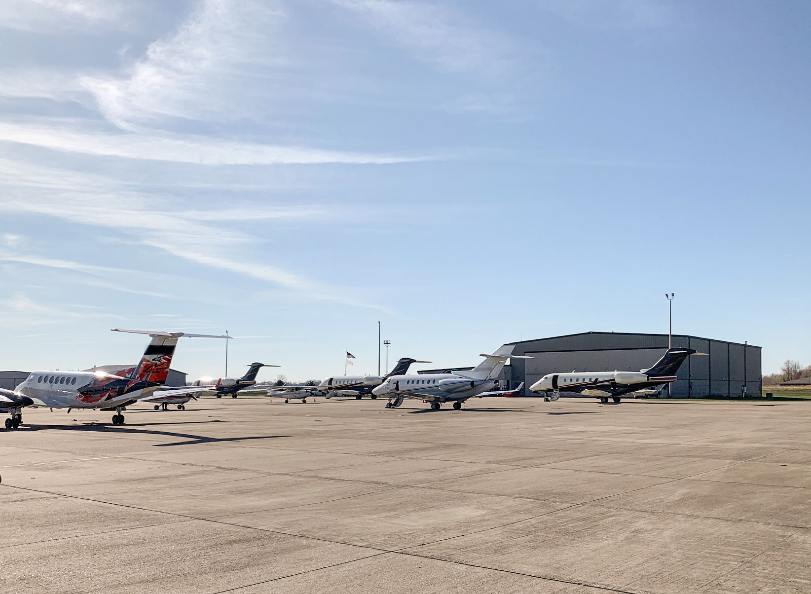 Photo of airplanes outside of an airport with a hangar in the background