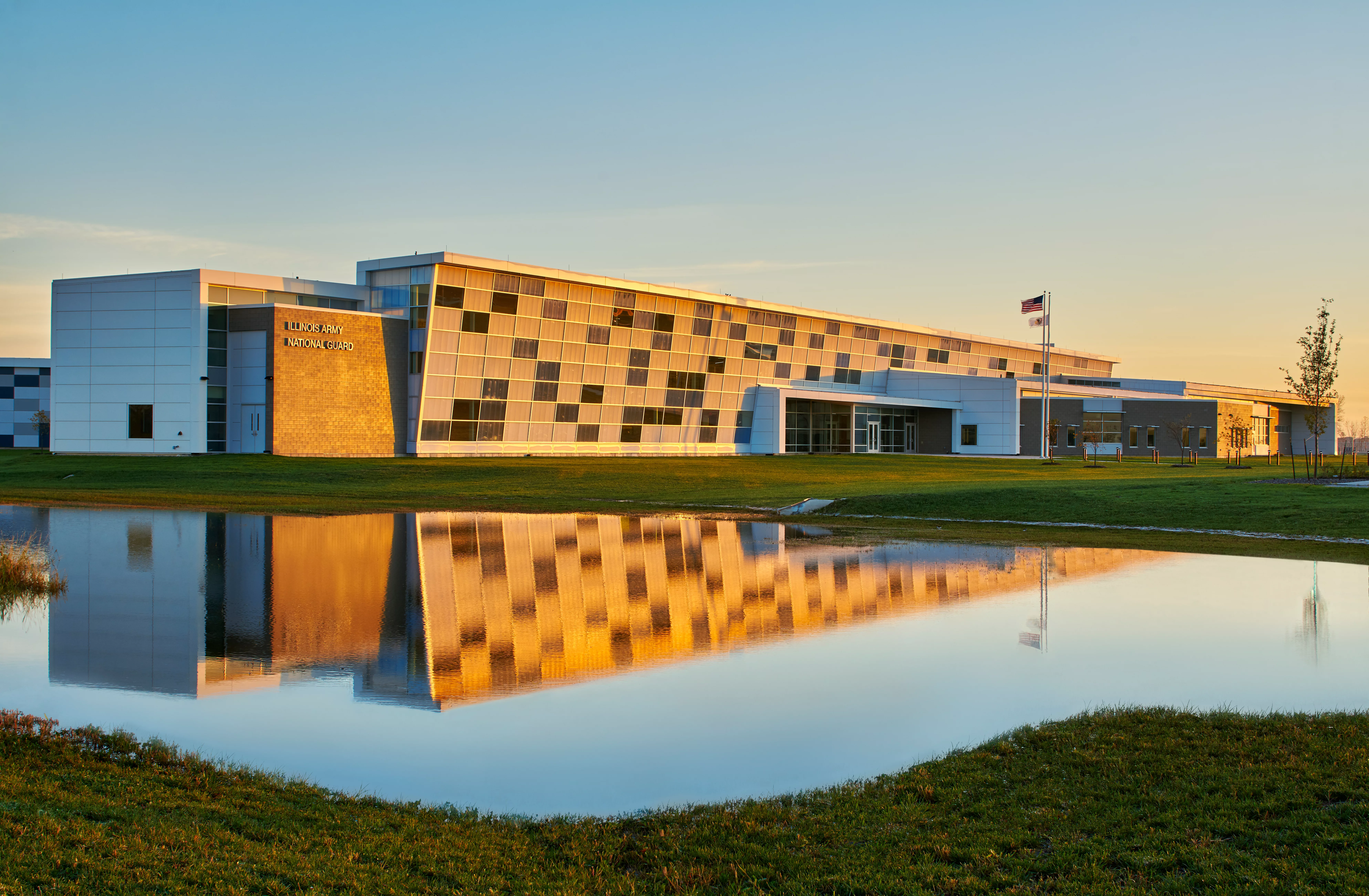 External photo of a building at sunset with a pond in front and multicolored facade
