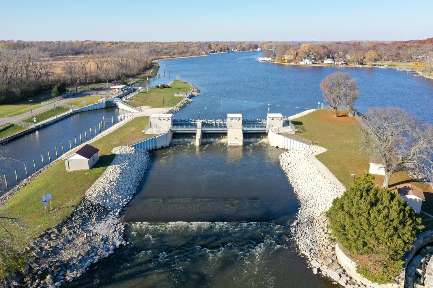 Aerial view of dam with water, grass and blue sky in background