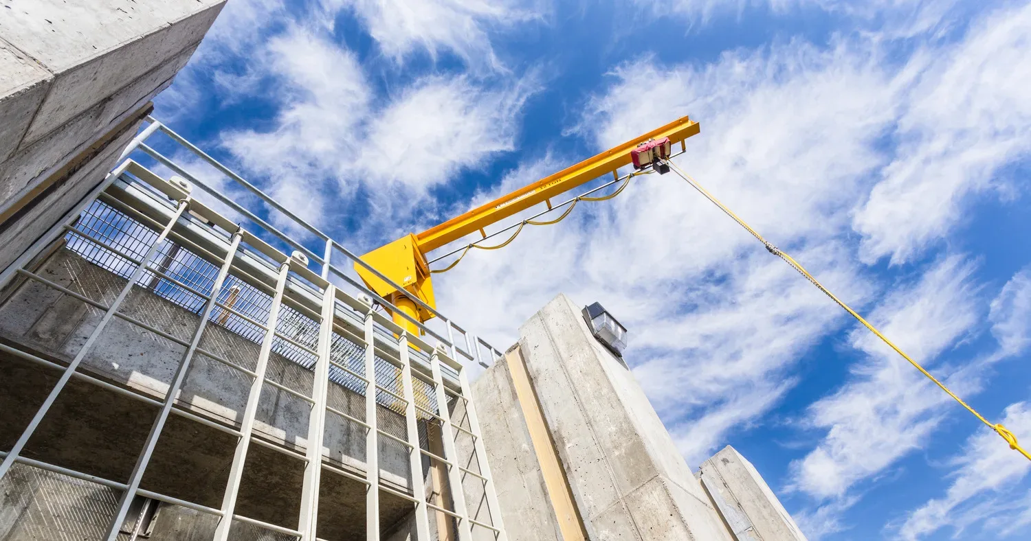 View looking up at part of a water control structure, painted yellow, against blue sky