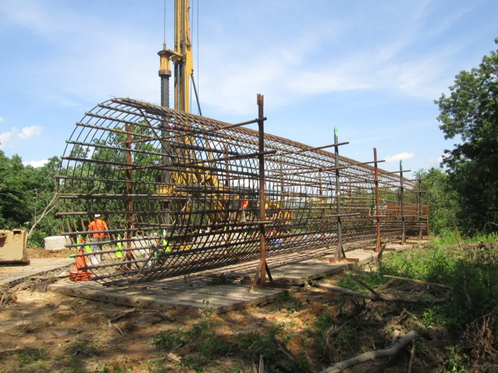 Transmission line foundation structure with blue sky and workers in background