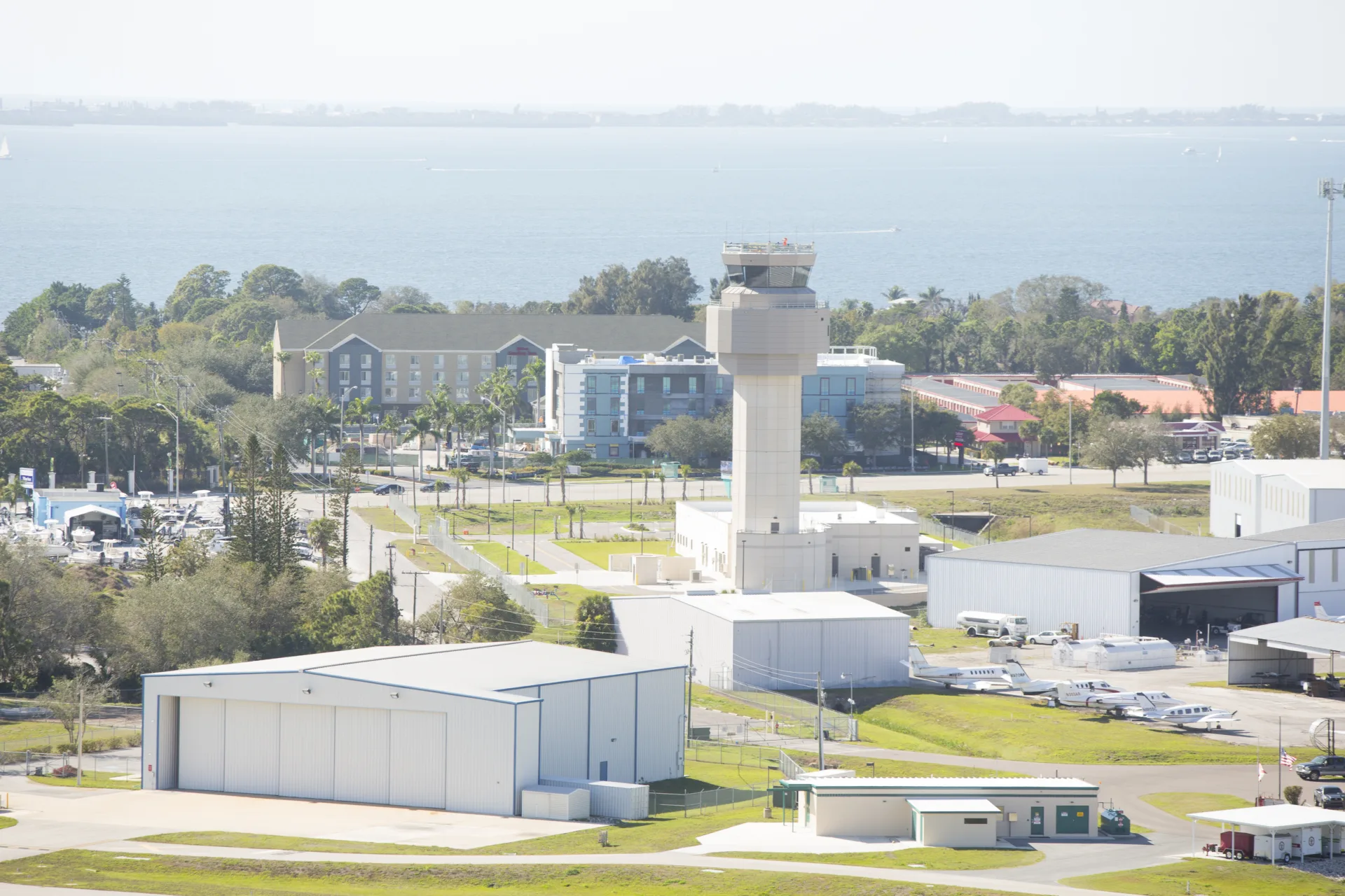 Close-up aerial image of an airport near a body of water, including an air-traffic control tower