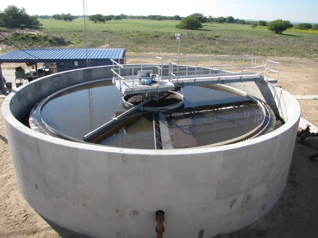 Wastewater treatment facility with grass and trees in background
