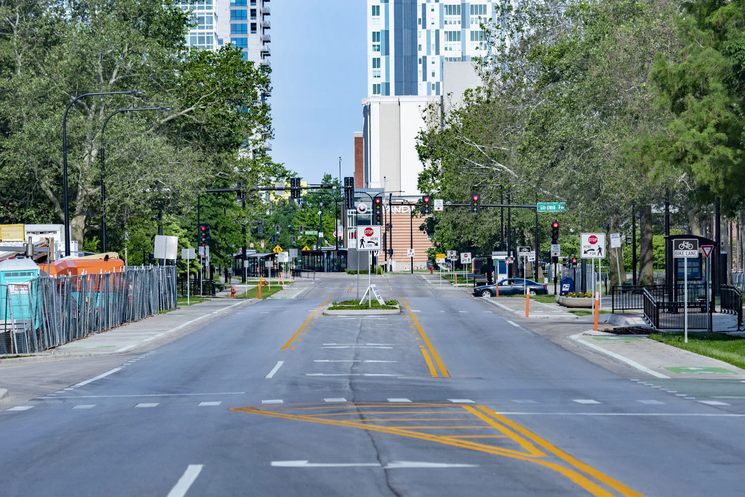 City street with yellow and white striping and traffic lights with buildings in the background