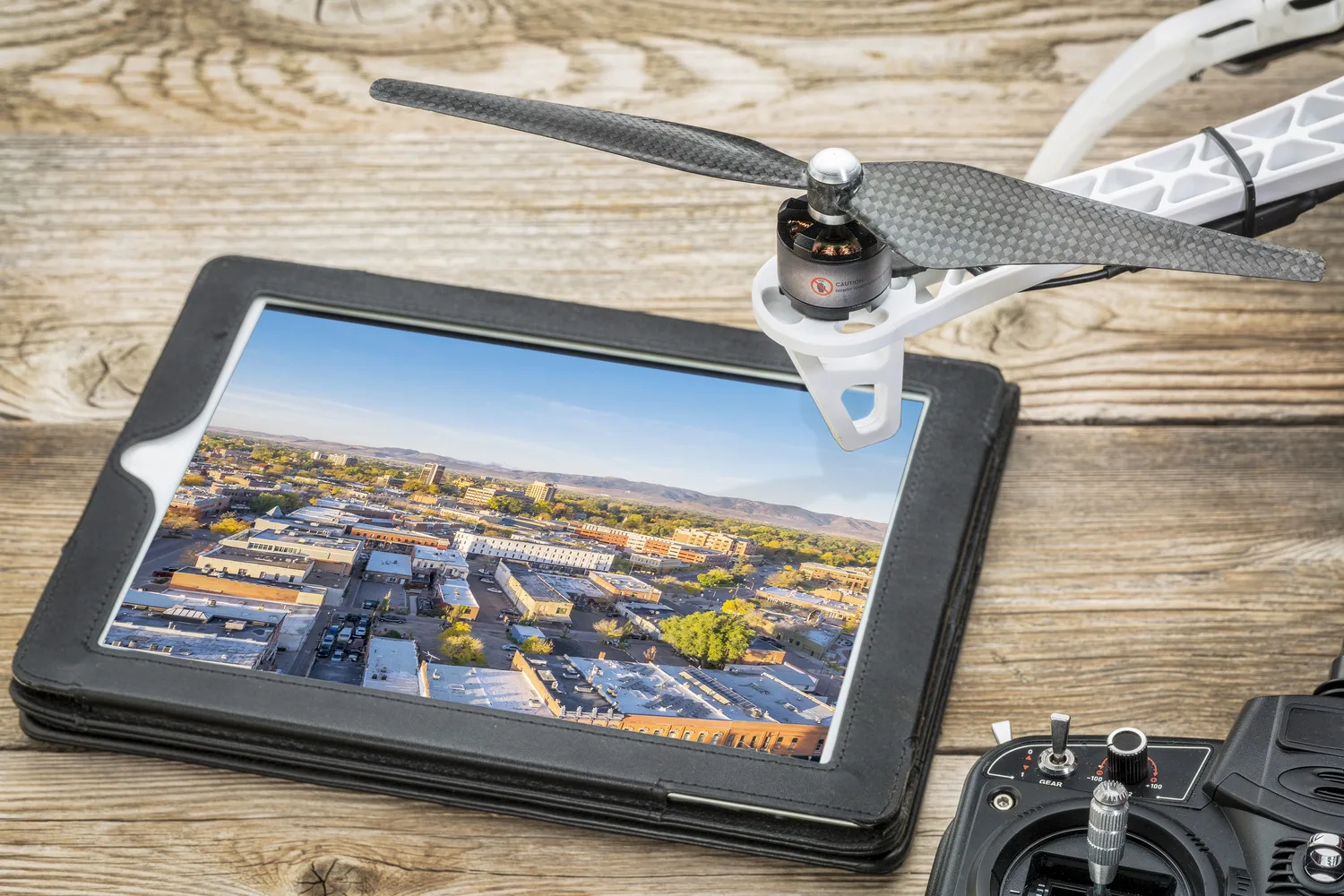 drone aerial photography concept - reviewing aerial pictures of Fort Collins downtown on a digital tablet with a drone rotor and radio control transmitter,