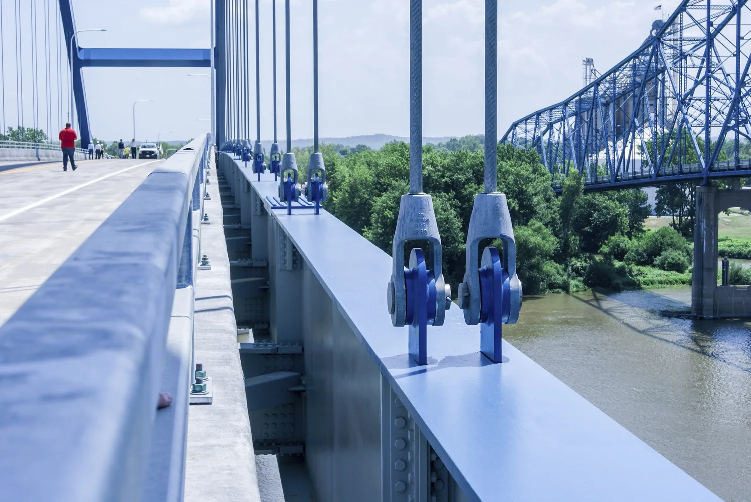 Close-up view of cables on blue bridge with trees in background