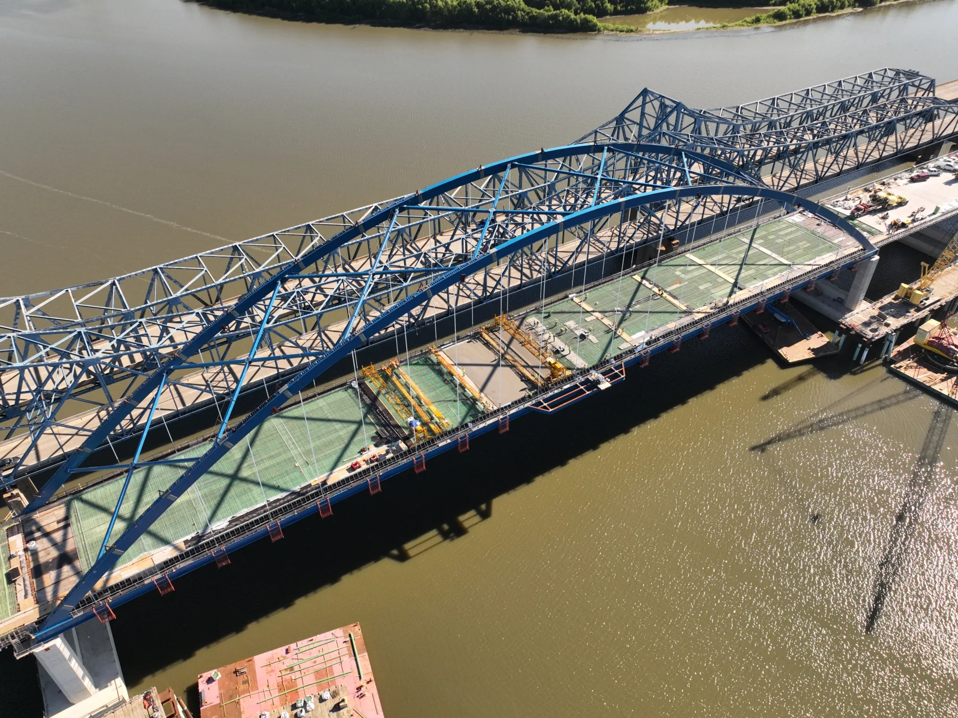 Aerial view of old bridge next to new arch bridge under construction over river