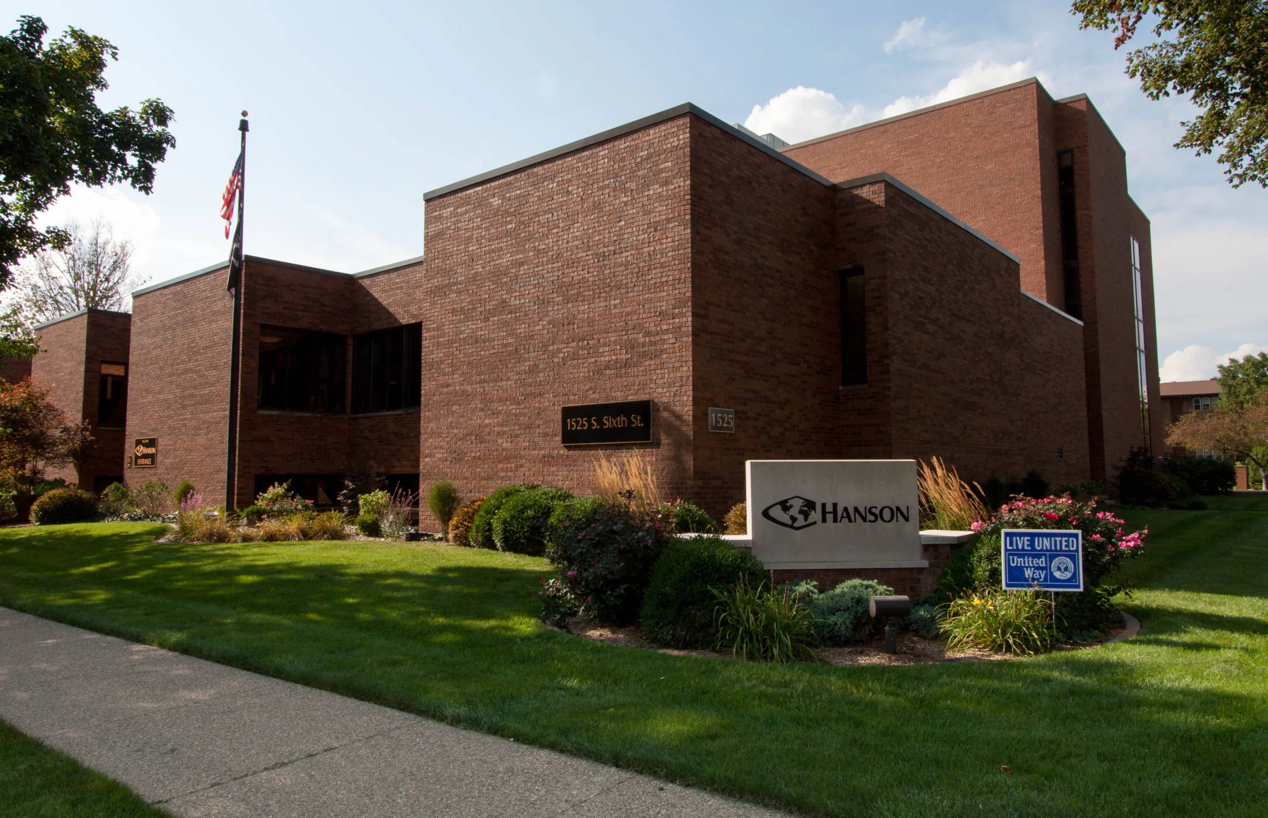 Exterior view of brown brick building, Hanson headquarters in Springfield, Illinois, with stone Hanson sign in front and green grass with colorful landscaping