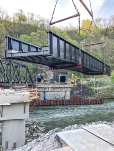 New bridge span in mid air as it is lowered during construction work on river