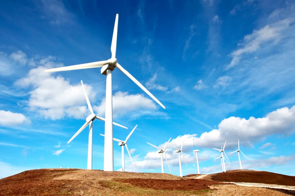Wind turbines with bright blue sky and puffy white clouds in background
