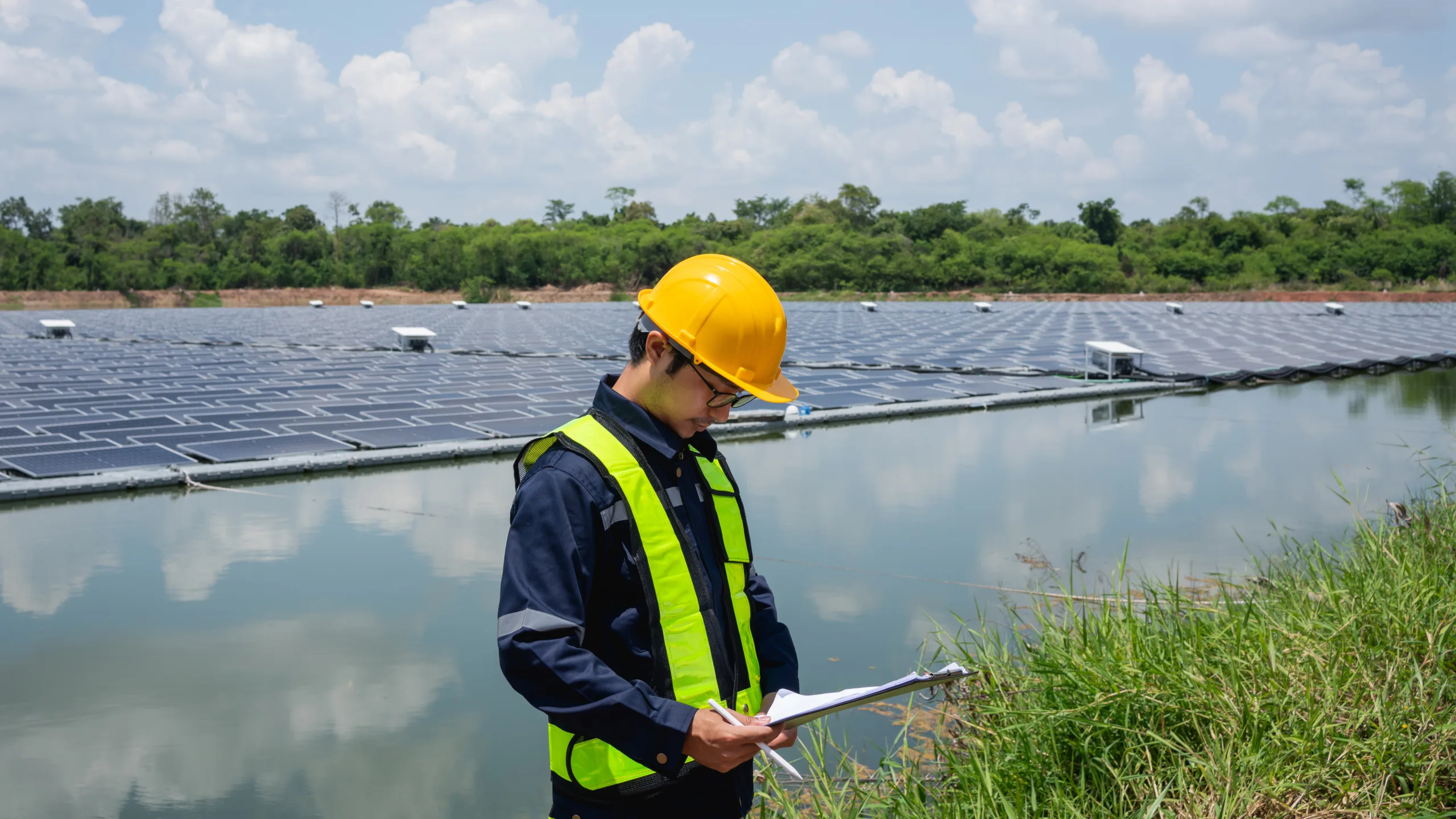 Engineer setting up floating solar panels on a platform in the lake. Worker is on-site, installing and maintaining the floating solar panel system on the water.