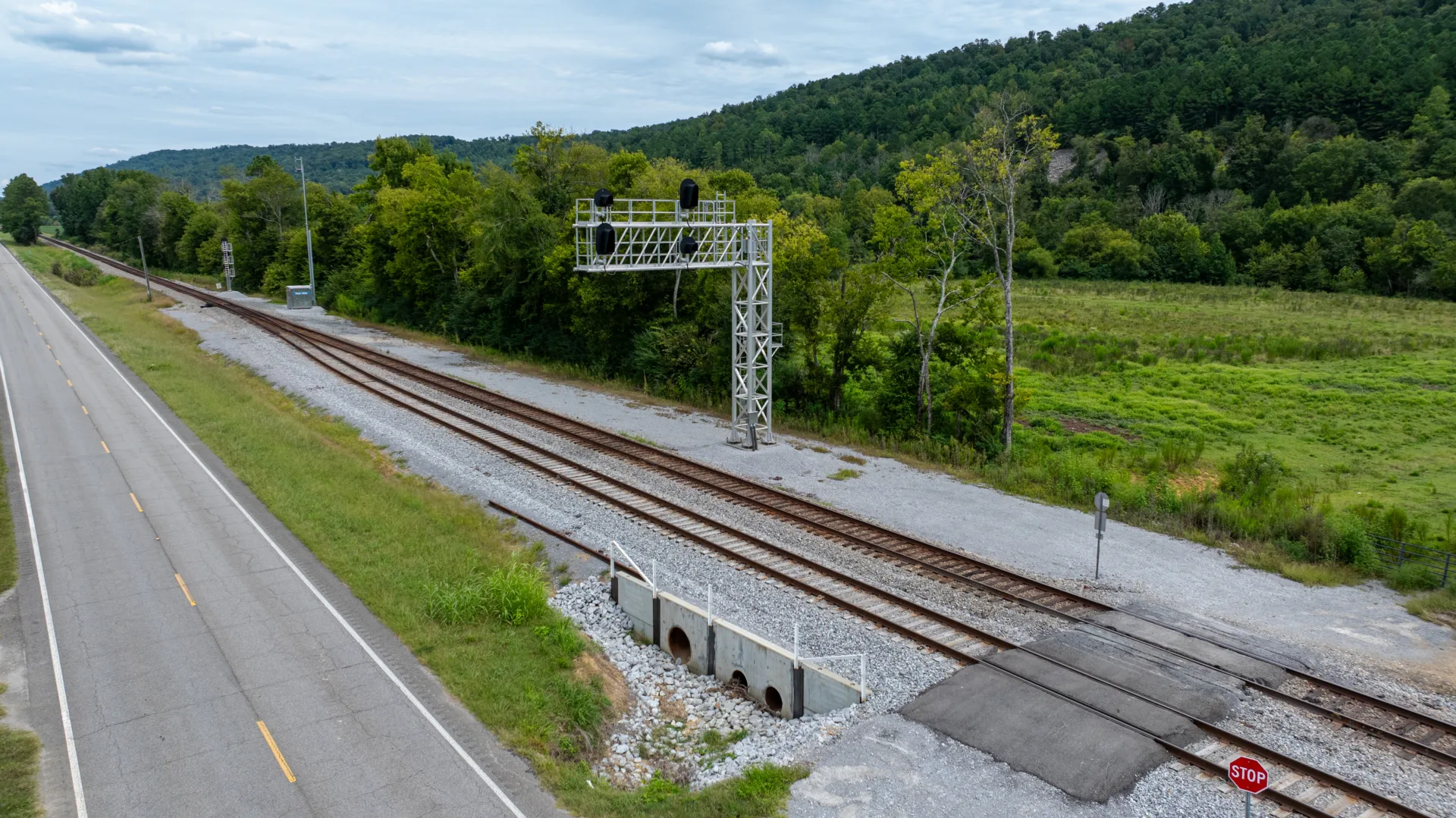 Aerial view of railroad tracks with greenery, trees and hills in background