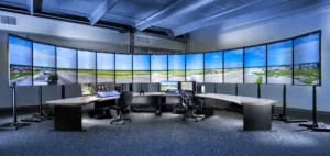View of the inside of a digital tower control center, with 10 vertical monitors showing an airfield