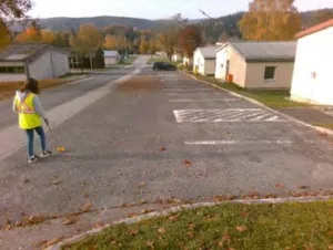image of woman in neon yellow safety vest using survey equipment in parking lot surrounded by low buildings