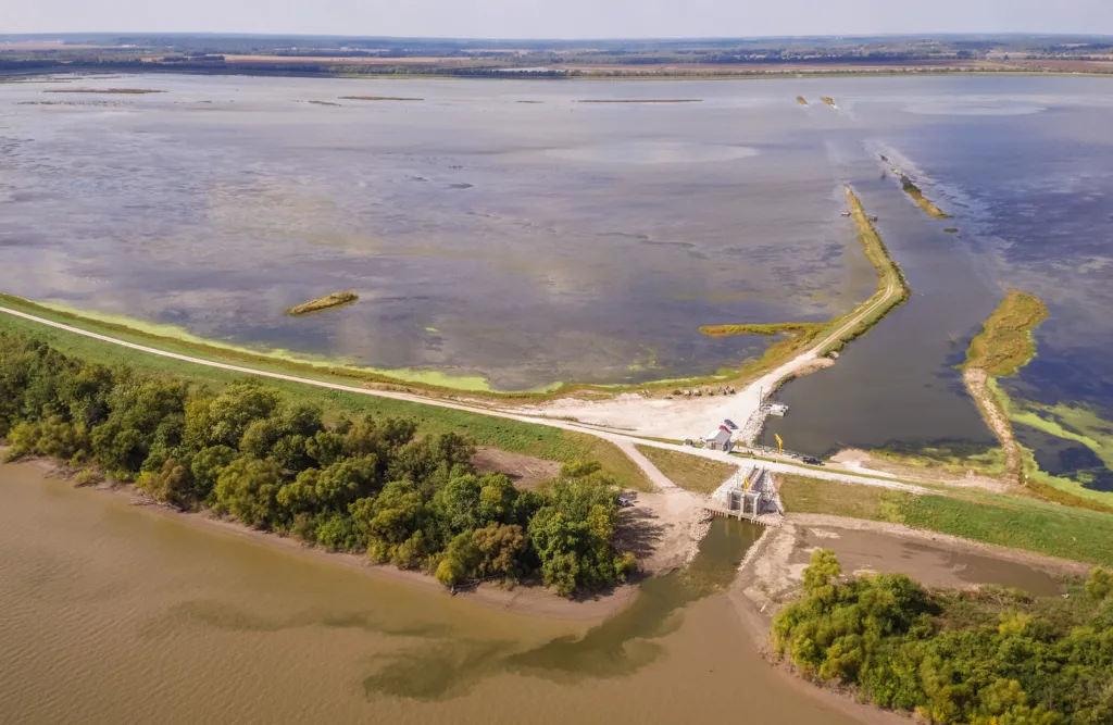 Aerial view of Emiquon Preserve, with trees and grassy land dividing two bodies of water, water control structure in center