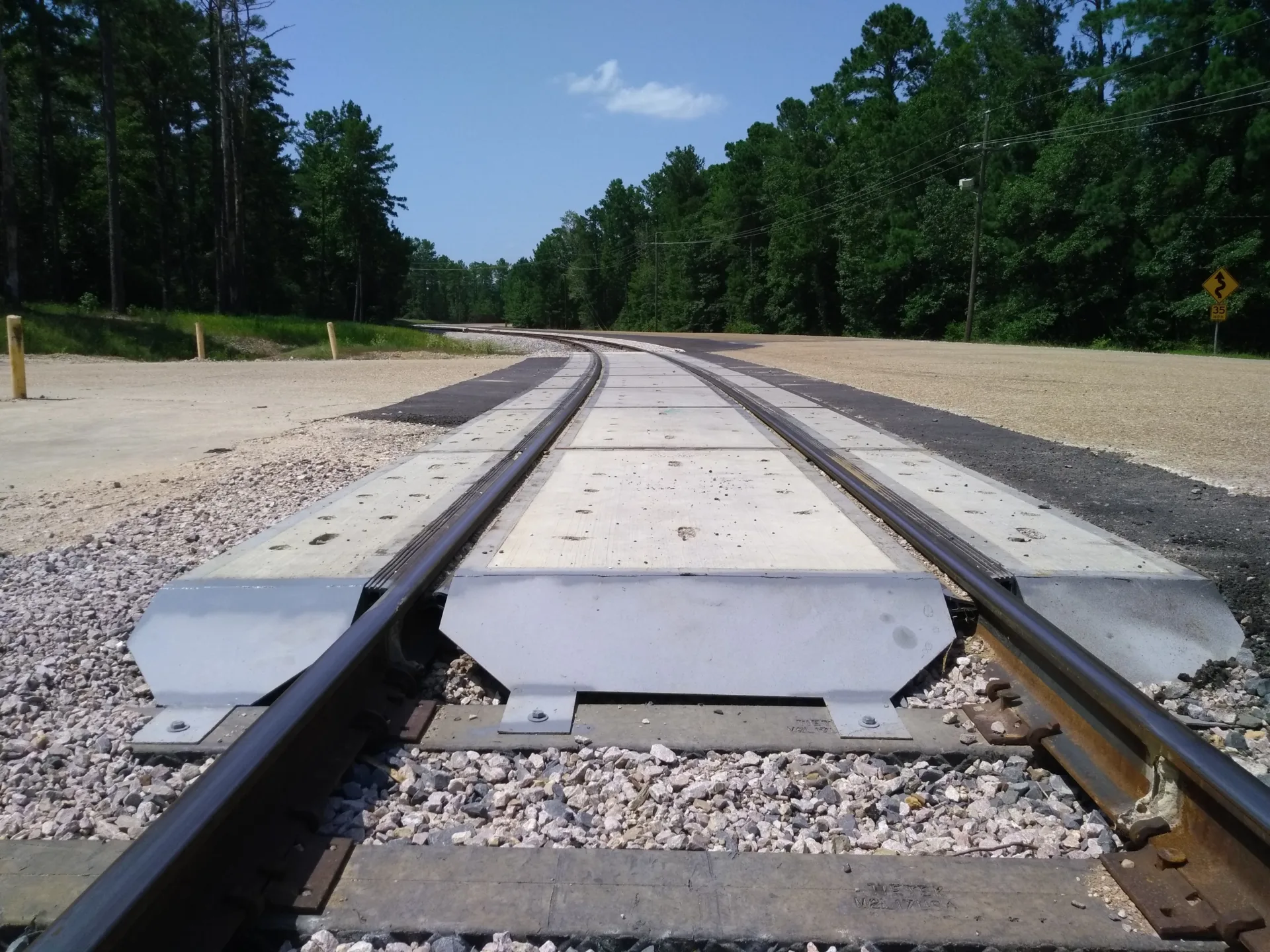 Ground-level close-up photo of a train track curving to the left in the distance, with trees on both sides