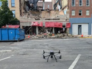 Close-up photo of a drone on the ground in front of a building destroyed by fire