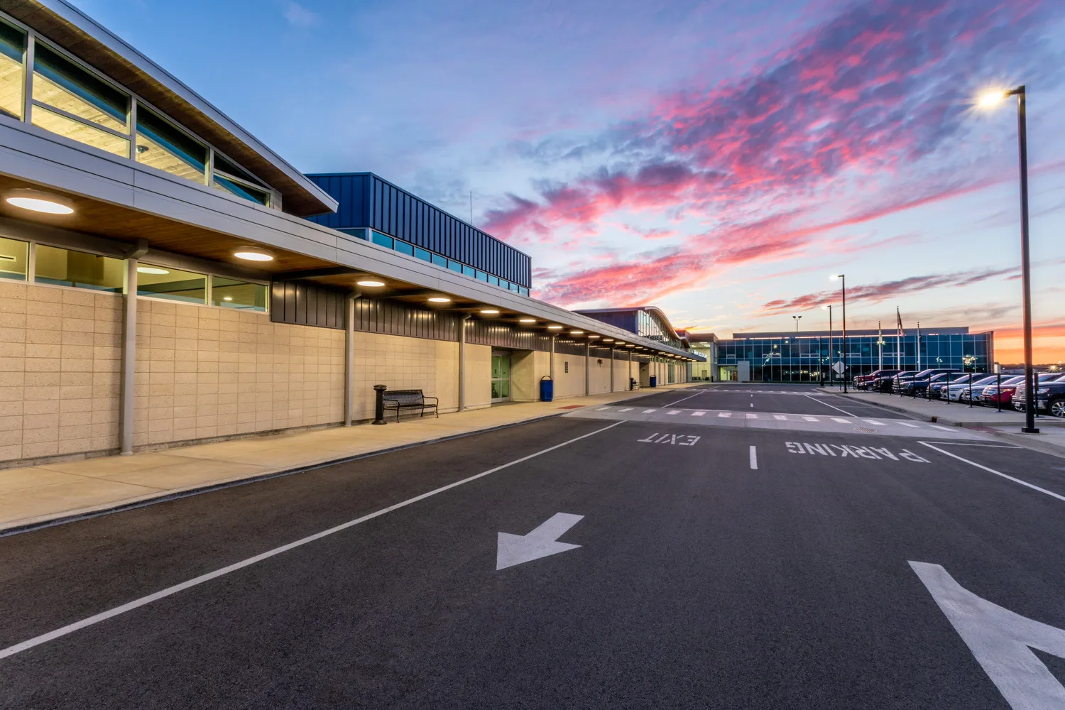 Dusk shot of an airport with terminal at left and parking lot at right