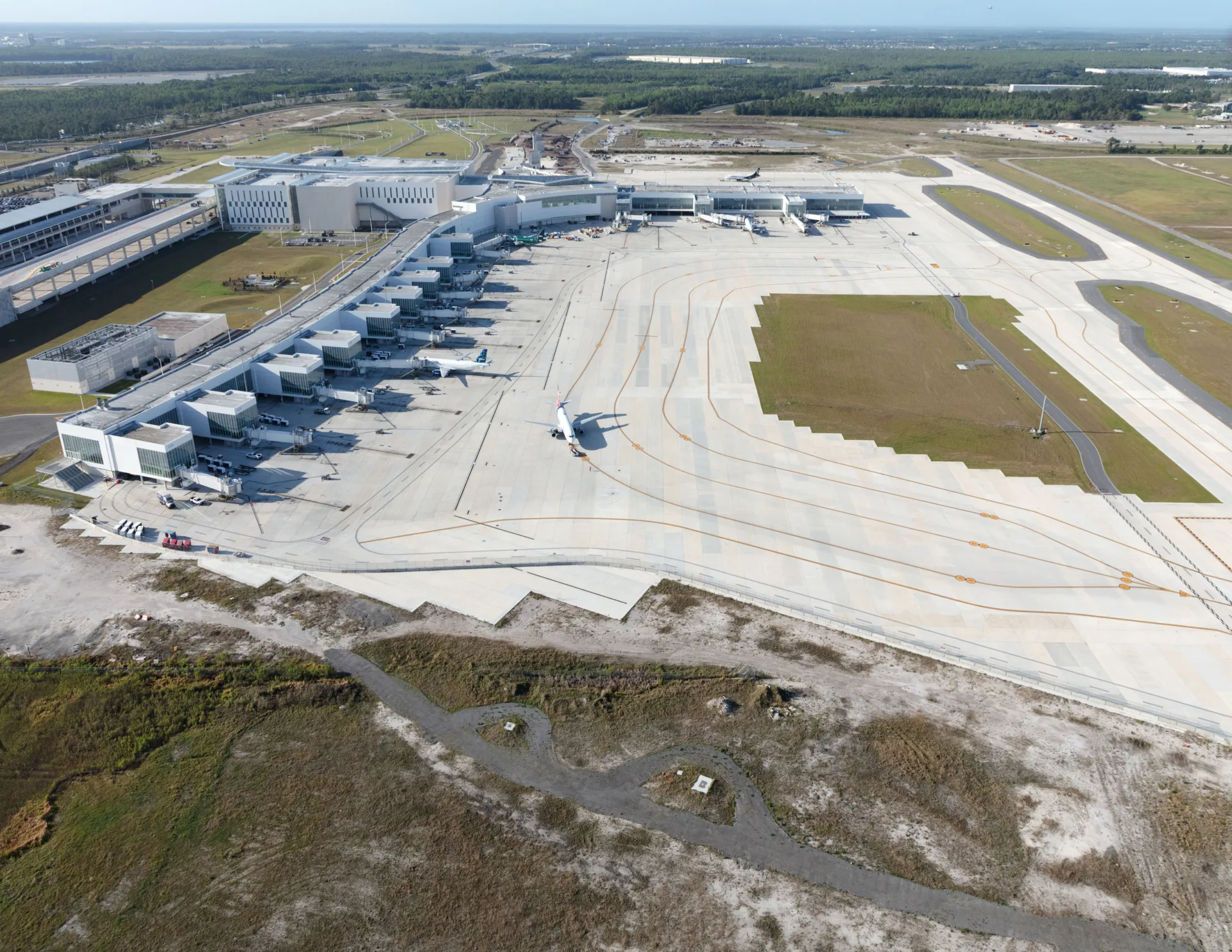 Aerial photo of airport terminal airside area with planes parked at gates and one pulling out
