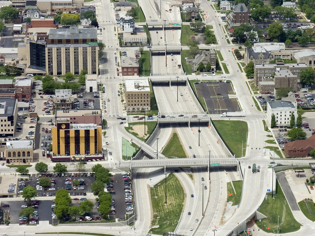 Aerial photo of a new interstate cutting through a city's downtown area, with buildings on each side of roadway