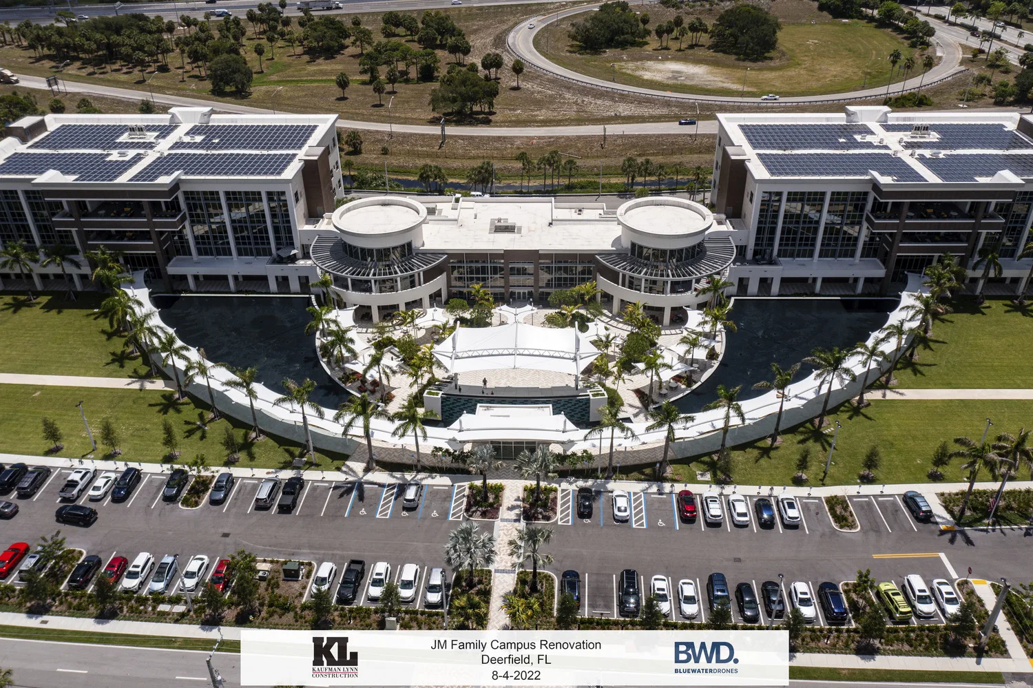 Aerial photo of a business complex with a parking lot in the foreground, half-circle entrance design and twin rotundas and rectangular structures on either side.