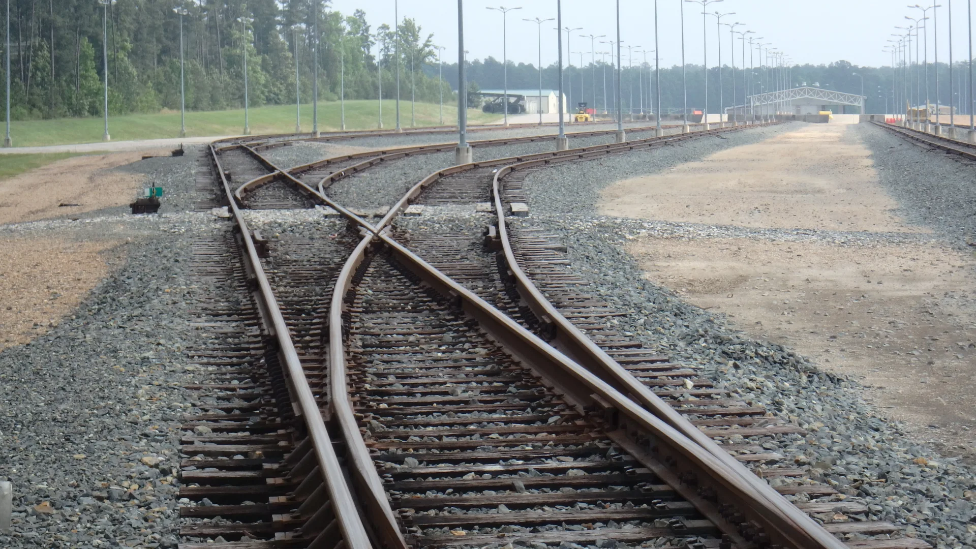 Ground view of multiple sets of railroad tracks leading to facility in distance