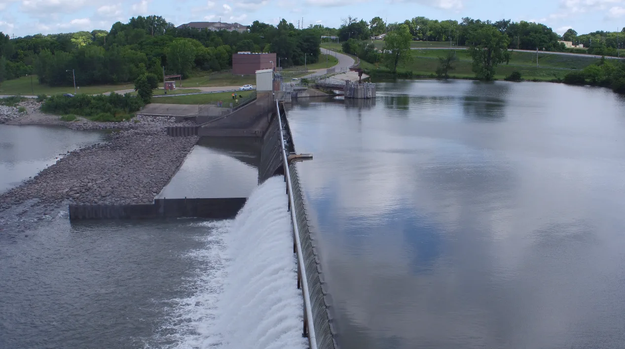 Aerial photo of dam with trees and small building in background