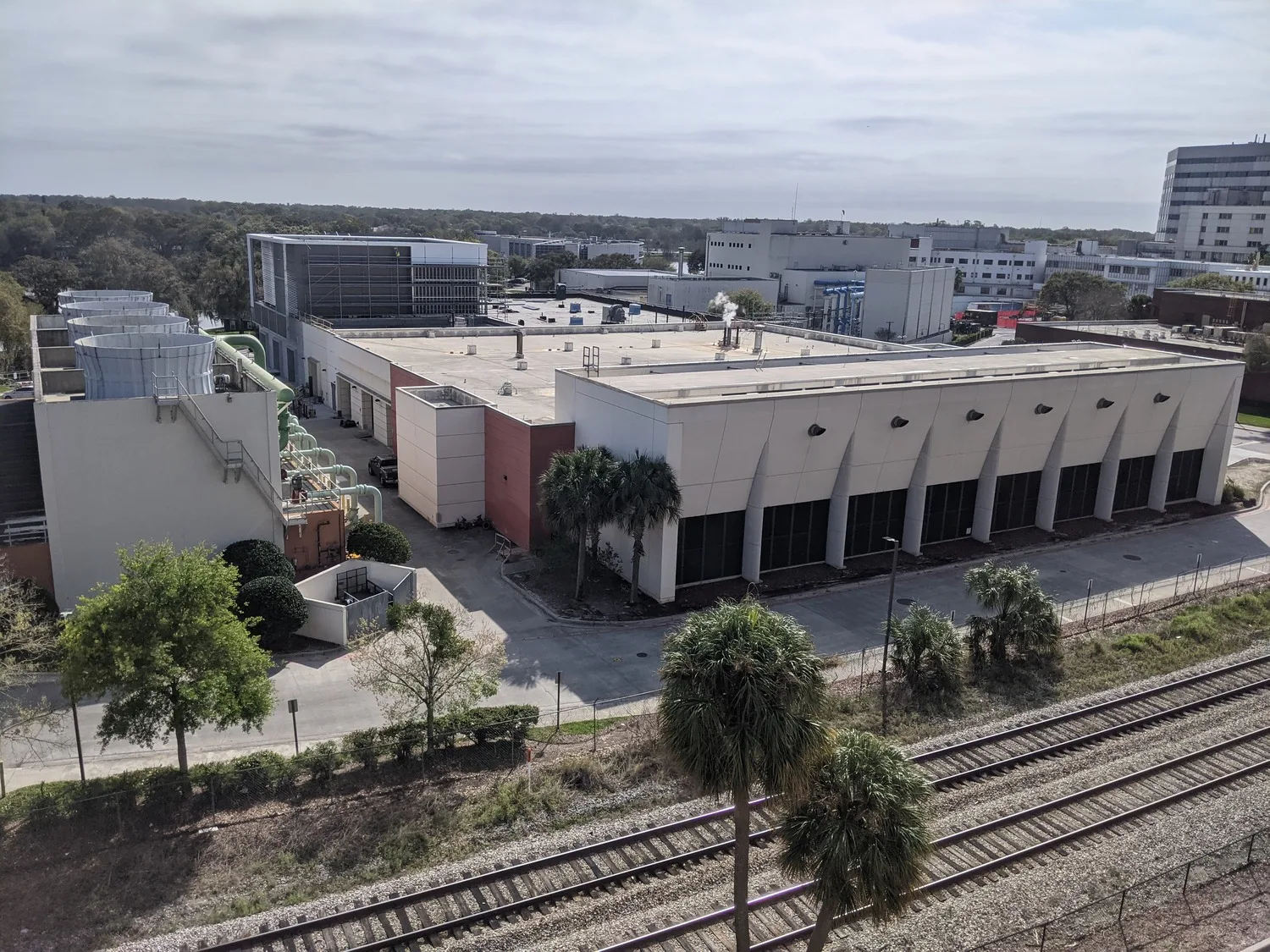 Aerial view of the exterior of a building with railroad tracks in the foreground and other buildings around it