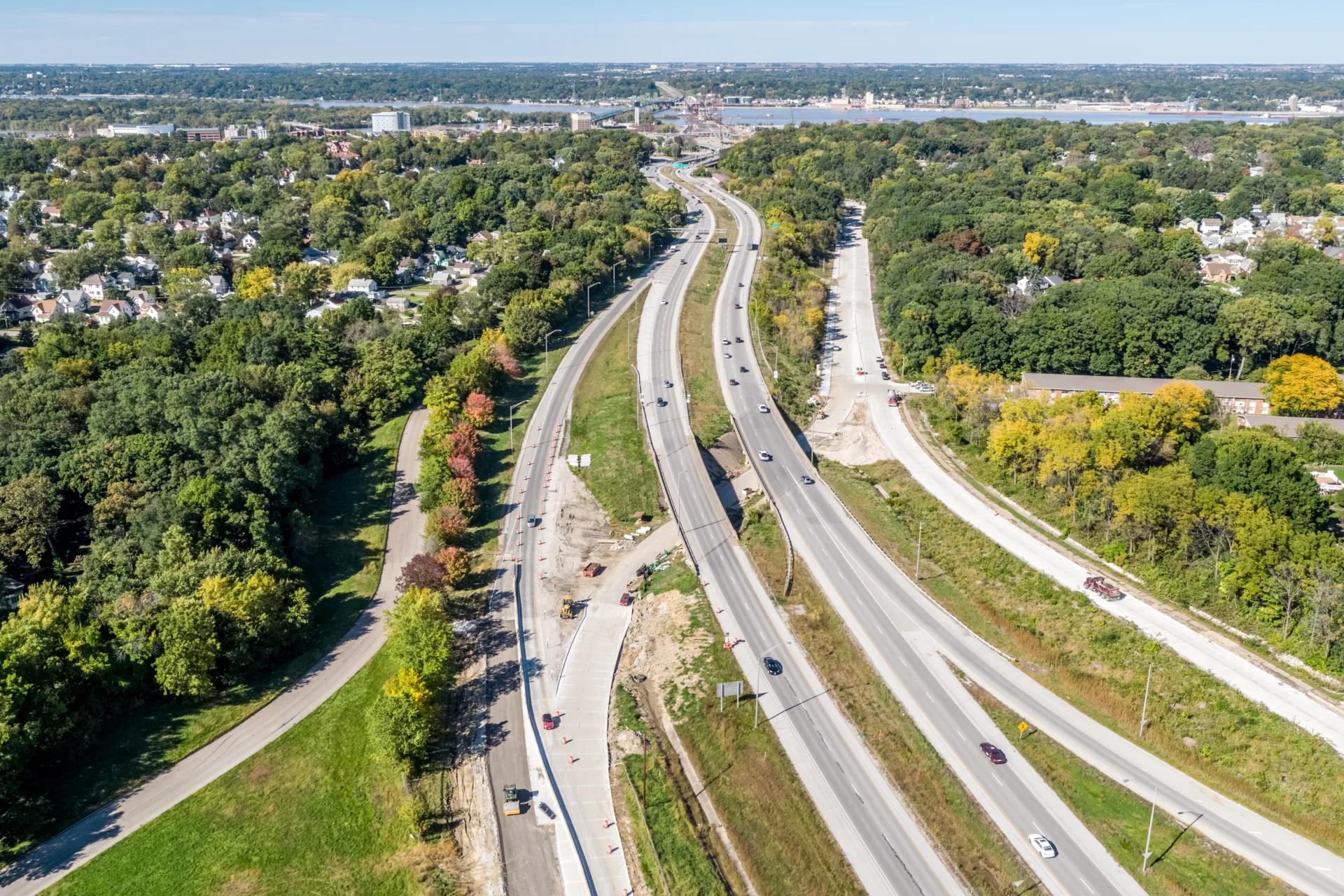 Aerial of interstate roadways with river on horizon and trees on either side