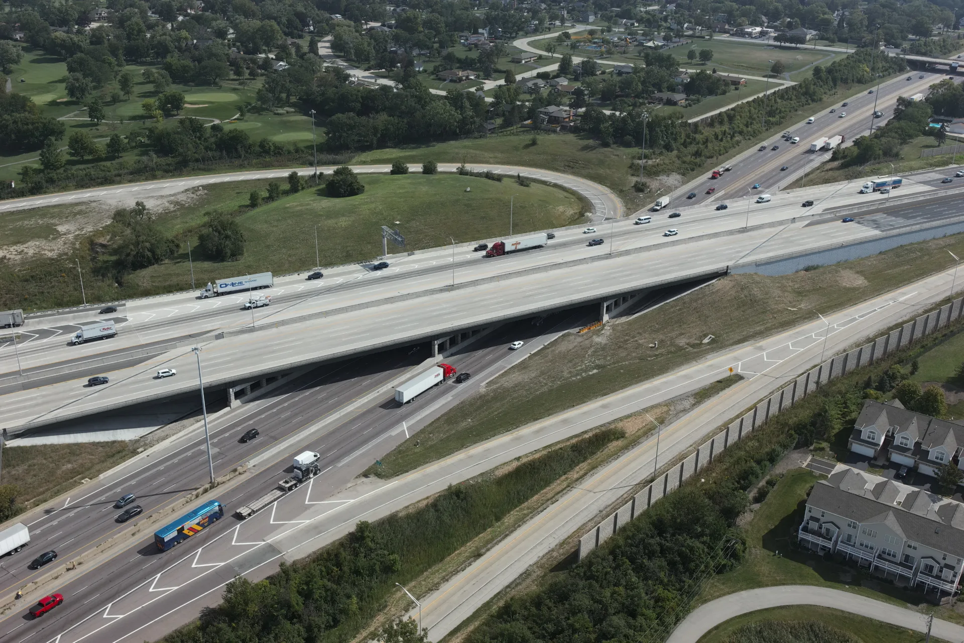 An aerial photo of one expressway passing under another, with an exit ramp in the right foreground