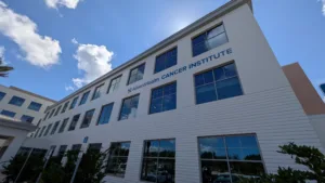 Exterior of building lined with windows with AdventHealth Cancer Institute on the side. Building photographed at angle.