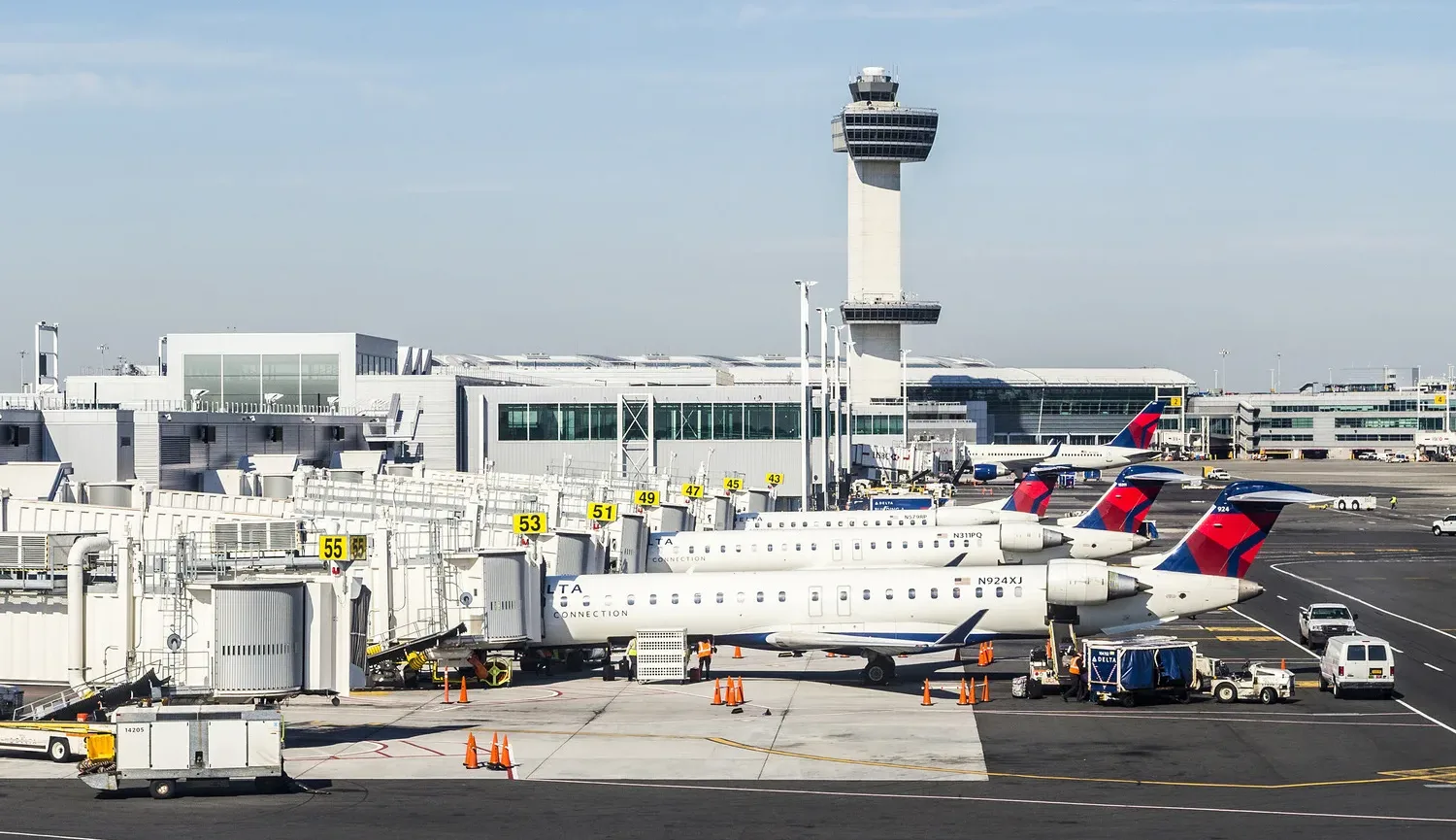 Air Traffic Control Tower and Terminal 4 with Delta airplanes at the gates in JFK Airport in NY.