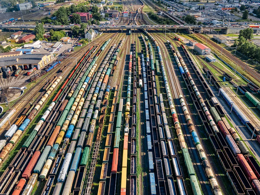 Aerial photo of lots of various wagons: tanks, platforms, dump trucks stay on railways at terminal. Cargo transportation of various goods by rail. Import and export logistics.